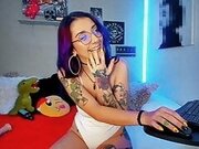 Colombian otaku webcamer girl with purple hair and tattoos looks very sensual while she broadcasts with a white bodysuit
