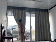 A handsome young man jerks off in front of a glass door.